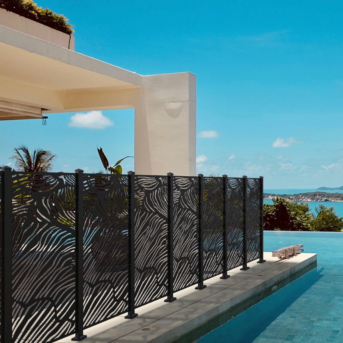 Black aluminum Sunbelly privacy screen with a Malibu palm leaf design surrounding a poolside patio at a luxury home.